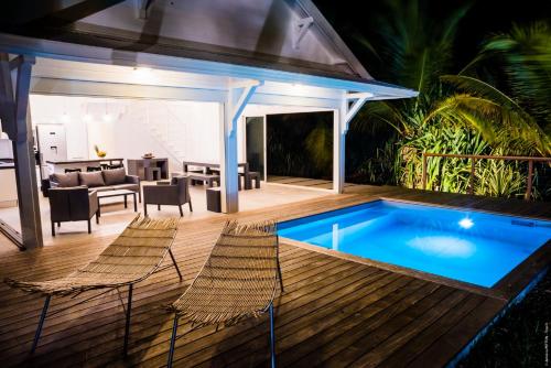 a backyard with a swimming pool and chairs and a house at Villa Ever Blue in Le Vauclin