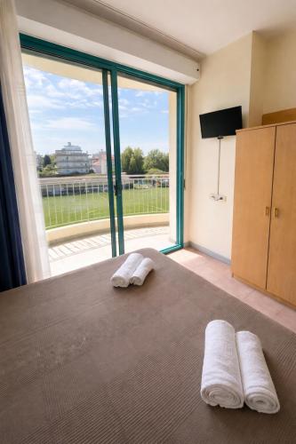 a bedroom with two white towels on a bed with a large window at Bellariva appartamenti in Rimini