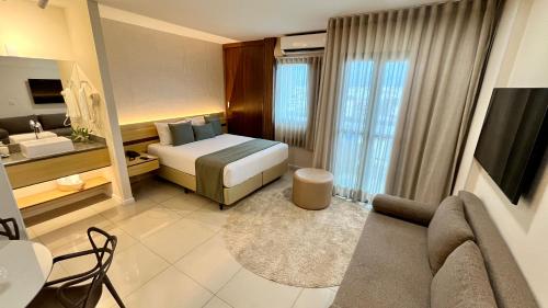 a hotel room with a bed and a couch at Flat PRAIA de Camburi in Vitória