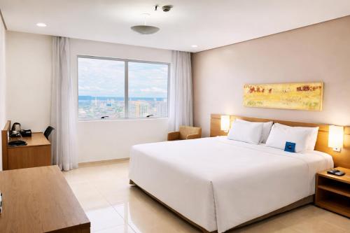 a bedroom with a white bed and a large window at Blue Tree Premium Manaus in Manaus