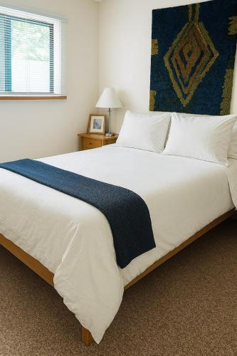 a large white bed with a blue blanket on it at Suite and Simple in Ucluelet