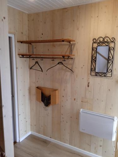a room with a wooden wall with a mirror and a shelf at Björkdahla in Dörarp