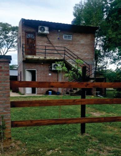a brick building with a balcony and a house at Cabaña Doña Adela in Paso de la Patria