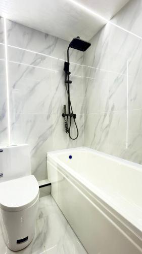 a white bathroom with a toilet and a bath tub at Modern Luxury Apartment Central Samarkand in Samarkand