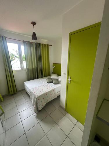 a bedroom with a bed and a green door at Studio N10 Résidence OBAYEAR in Schœlcher