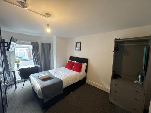 a bedroom with a bed with red pillows and a chair at Cozy studios in Nottingham in Nottingham