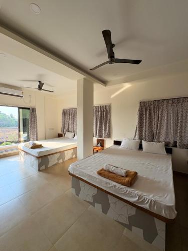 a bedroom with two beds and a large window at Hotel Ashoka Kokan Ganpatipule in Ganpatipule