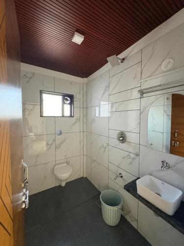 a bathroom with a sink and a toilet at Hotel Ashoka Kokan Ganpatipule in Ganpatipule