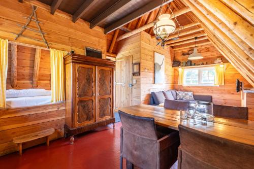 a dining room with a large wooden table in a cabin at Unieke plaggenhut in Drenthe met bedstee & uitzicht op wijngaard in Ruinerwold