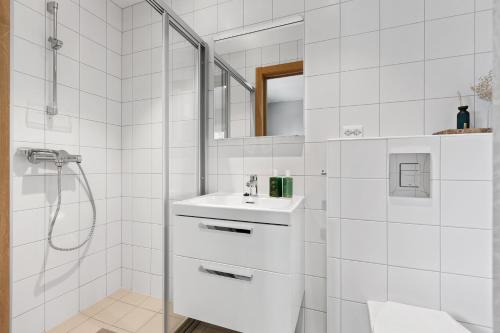 a white bathroom with a sink and a shower at Svolvær Panorama City Suite in Svolvær