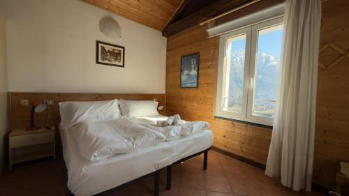 ein Schlafzimmer mit einem Bett mit weißer Bettwäsche und einem Fenster in der Unterkunft Hotel Al Pelmo in Pieve di Cadore