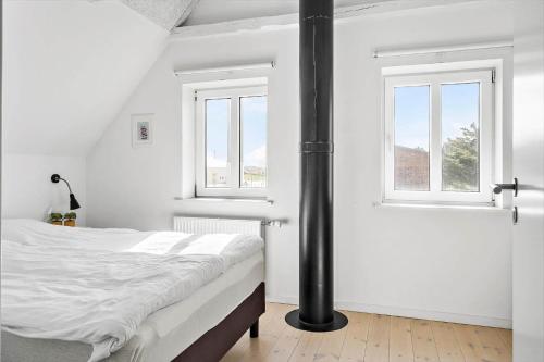a white bedroom with a bed and two windows at 704-Thyboron-Kirkevej-6 in Thyborøn
