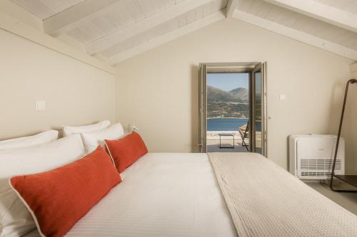 a white bedroom with a large bed with orange pillows at Nest Limeni in Limeni