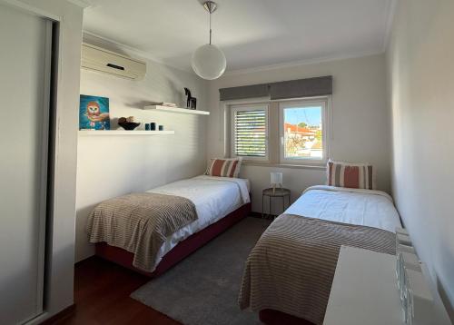 a bedroom with two beds and a window at Vivenda espaçosa com jardim e churrasqueira in Alcabideche