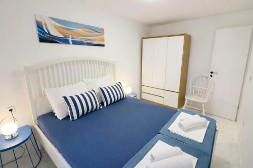 a small bedroom with a blue bed and a chair at Apartman Lucija in Selce
