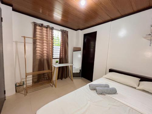 a bedroom with a white bed with a wooden ceiling at Shiloh Homestay in General Luna