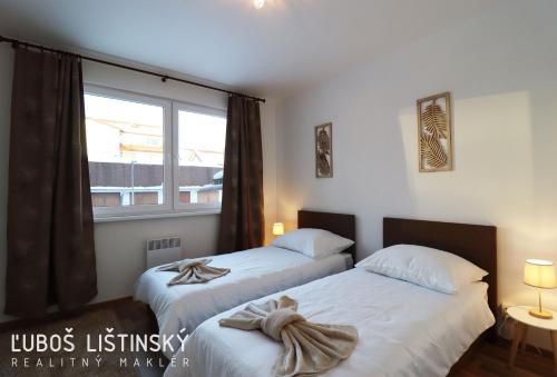 two beds in a room with a window at Apartman Pod Vysokymi Tatrami in Nová Lesná
