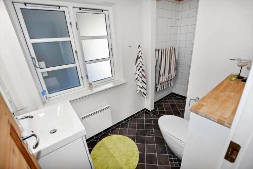 a bathroom with a toilet and a sink and a window at 0379-Romo-Stormengevej-14 in Høm