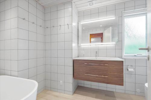 a white tiled bathroom with a sink and a mirror at 0127-Romo-Umanaksvej-4 in Høm