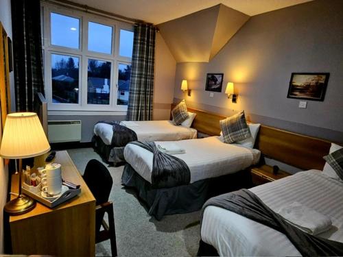 a hotel room with three beds and a window at St Michaels Hotel in St. Michaels