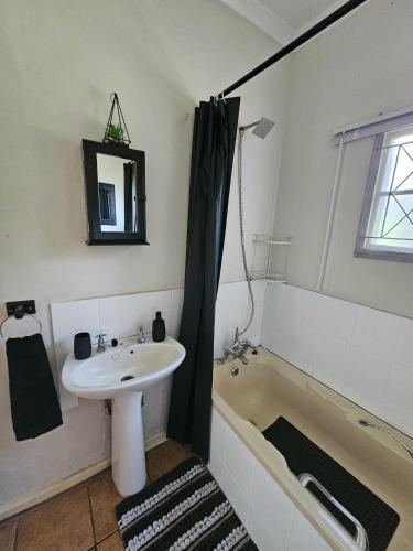 a bathroom with a sink and a bath tub next to a sink at Schuilhoek Farm House at Ngweni Private Game Farm in Hluhluwe