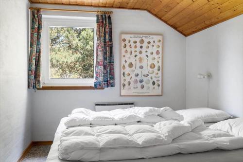 a large white bed in a room with a window at 0326-Romo-Sandloberen-3 in Høm