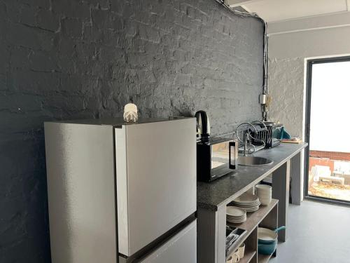a kitchen with a refrigerator and a black wall at Blue Moon Charming 2 Bed Poolside Apartment in Bellville