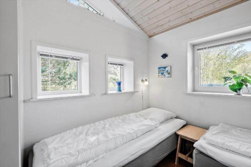 a small bedroom with a bed and two windows at 0403-Romo-Lyngvejen-44-C in Høm