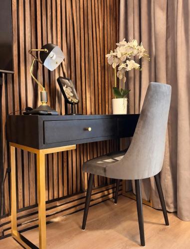 a desk with a chair and a lamp and flowers at Modern 2-Room Apartment with Large Balcony & Private Parking in Gdańsk