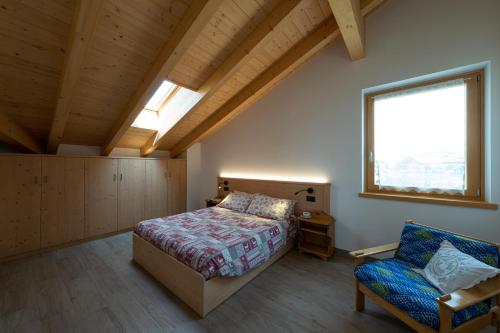 a bedroom with a bed and a chair and a window at Agritur Rizzi di Inama Ugo in Coredo