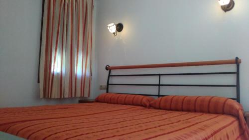 Un dormitorio con una cama con una manta naranja. en La Alberquilla, en Yeste