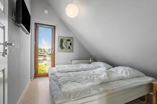 a white bedroom with a bed and a window at 0344-Romo-Vestergade-331 in Høm