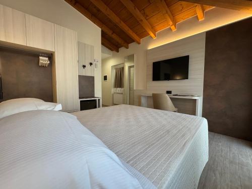 a bedroom with a large white bed and a television at Hotel Roma in Garda