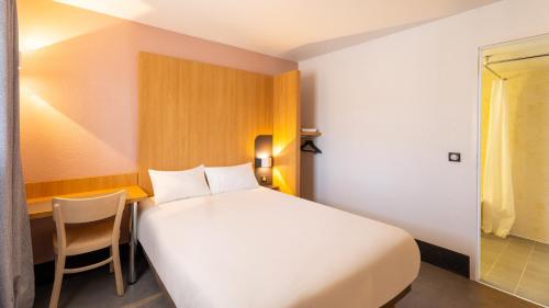 a bedroom with a large white bed and a chair at Kyriad ECO - Lorient Lanester in Lanester