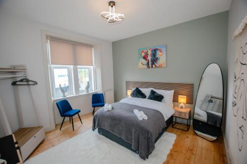 a bedroom with a bed and two chairs and a mirror at Limefield Residence in West Calder