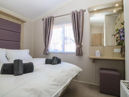 a bedroom with a large white bed and a window at Pheasant Lodge in Holyhead