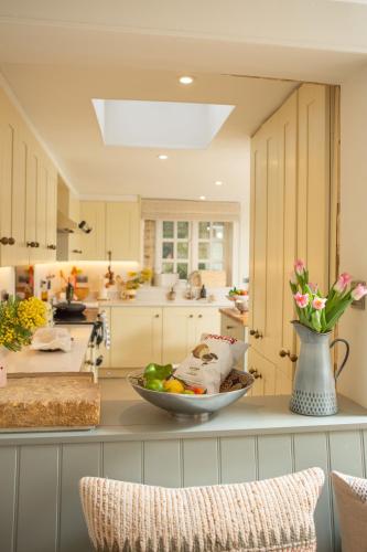 a kitchen with a bowl of fruits and vegetables on a counter at The Cottage - Elegant 3 Bedroom Cottage in the Heart of Stow-on-the-Wold in Stow on the Wold