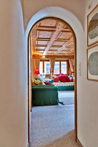 an archway in a living room with a couch at Chesa Grischuna 4pax - Madulain in Madulain