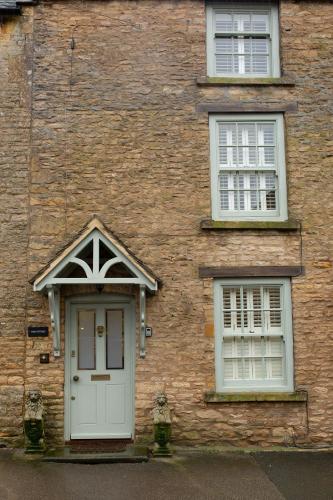 a brick building with a door and two windows at The Cottage - Elegant 3 Bedroom Cottage in the Heart of Stow-on-the-Wold in Stow on the Wold