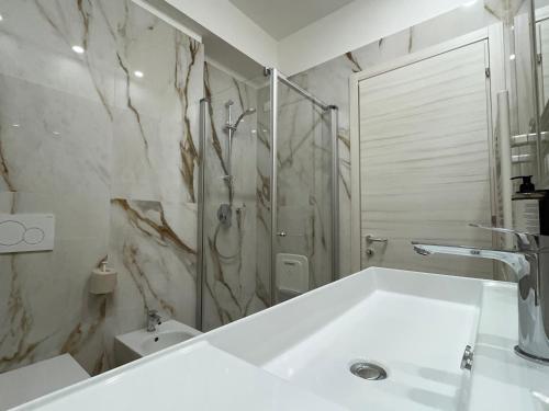 a white bathroom with a shower and a sink at Hotel Roma in Garda