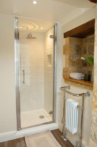 a shower with a glass door in a bathroom at The Cottage - Elegant 3 Bedroom Cottage in the Heart of Stow-on-the-Wold in Stow on the Wold