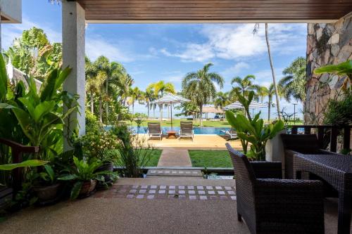 a patio with a view of a pool and palm trees at Beachfront! 2 Bedroom Apartment A4 - 110 Sqm in Ko Bu Bu