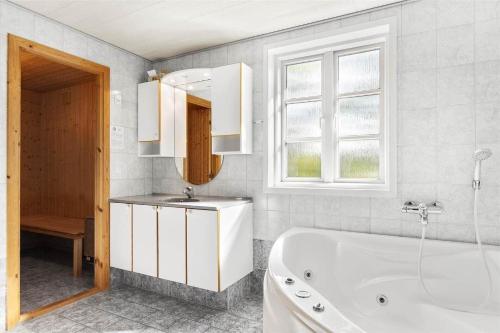 a bathroom with a tub and a sink and a mirror at 0227-Romo-Kromosevej-17 in Høm
