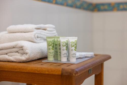two tubes ofodorizers sitting on a wooden table with towels at Sangiorgio Resort Hotel & Spa with restaurant in Cutrofiano