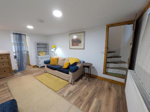 a living room with a blue couch with yellow pillows at Bright cottage, sleeps 4, near trails, own parking in Abercarn