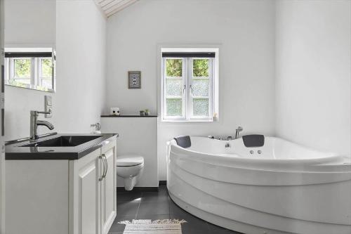 a white bathroom with a large tub and a sink at 0130-Romo-Ejnar-Mikkelsensvej-22 in Høm