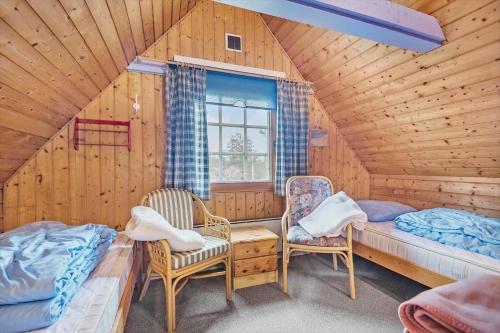 a bedroom with two beds and two chairs in a cabin at 0162-Romo-Rabjergvej-97 in Høm