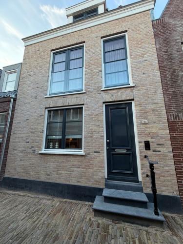a brick house with a black door and windows at Luxe 3-kamer Penthouse met dakterras in het centrum van Hoorn in Hoorn