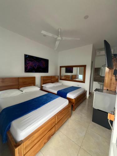 a bedroom with two beds and a flat screen tv at Hotel Boutique Primavera Beach in Necoclí