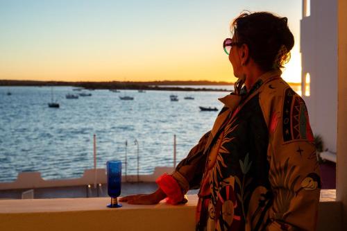 a woman standing on a balcony looking out at the water at Formentera Especial in La Savina